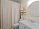 Well-lit bathroom featuring a white vanity, round mirror, and shower with patterned curtain at 1012 Chestnut Creek Dr, Villa Rica, GA 30180