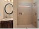 Bathroom with glass-door tiled shower, cabinet vanity, and round mirror at 10565 Highgate Manor Ct, Duluth, GA 30097
