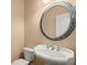 Bathroom featuring a pedestal sink with designer fixtures and a decorative round mirror at 10565 Highgate Manor Ct, Duluth, GA 30097