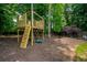 Outdoor play structure with climbing wall, slide, and swing in a wooded backyard setting at 6105 Overlook Park Dr, Cumming, GA 30040