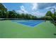 Community tennis courts with green and blue surface surrounded by mature trees at 6105 Overlook Park Dr, Cumming, GA 30040