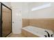 A soaking tub with jets is surrounded by neutral toned tiles adjacent to the glass shower at 218 South Se Ave, Atlanta, GA 30315