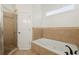 Bright bathroom featuring a soaking tub with jets, a separate glass-enclosed shower, and tiled walls at 218 South Se Ave, Atlanta, GA 30315