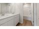 Bathroom with dual sink vanity with white cabinets, quartz counters, wood-look flooring, and tub with shower at 4036 Trimrose Ct, Atlanta, GA 30349