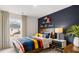 This playful bedroom includes a dark accent wall, fun shelving decor, and a bed with a colorful comforter at 11408 Gray Branch Dr, Lawrenceville, GA 30045