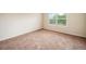 A bright and cozy bedroom features carpeted floors and a window overlooking lush greenery at 212 Jetta Cir, Mcdonough, GA 30253