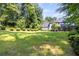 Expansive backyard featuring lush greenery and a charming two-story home in the background at 4220 Singing Post Ne Ln, Roswell, GA 30075