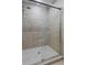 Walk-in shower featuring stone tile and sliding glass door at 4220 Singing Post Ne Ln, Roswell, GA 30075
