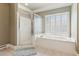 Bathroom with a glass shower, soaking tub, and a window with plantation shutters at 952 Moores Walk Ln, Suwanee, GA 30024