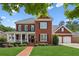 Charming two-story brick home with a welcoming front porch, manicured lawn, and attached two-car garage at 952 Moores Walk Ln, Suwanee, GA 30024