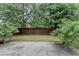 A fenced backyard, bordered by mature trees and rose bushes, features a concrete patio at 2280 Copper Trail Ln, Buford, GA 30519