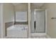A bathroom featuring a separate shower and tub with tile surround and window with privacy blinds at 2280 Copper Trail Ln, Buford, GA 30519