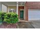 Welcoming front entrance with a green door, a welcoming mat, brick accents, and neat landscaping at 2280 Copper Trail Ln, Buford, GA 30519