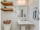 A neutral powder room with floating shelves, pedestal sink, decorative mirror, and wood-look flooring at 28 Rolling Rock Way, Dallas, GA 30157
