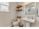 A neutral powder room with floating shelves, pedestal sink, decorative mirror, and wood-look flooring at 28 Rolling Rock Way, Dallas, GA 30157