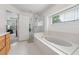 Bright primary bathroom featuring a soaking tub, glass-enclosed shower, and an adjacent main bedroom at 3652 Morning Creek Ct, Suwanee, GA 30024