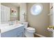 Charming bathroom with blue vanity, round window, and decorative wall art at 3652 Morning Creek Ct, Suwanee, GA 30024