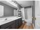 Stylish bathroom featuring a double sink vanity with gray cabinets, wood flooring, and a shower-tub combination at 3652 Morning Creek Ct, Suwanee, GA 30024