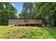 Rear view of the house with wooden deck, surrounded by lush greenery and mature trees at 1010 Martin Ln, Canton, GA 30114