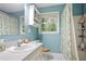 This bright blue bathroom features a quartz countertop, white vanity, shower/tub combo and decorative shower curtain at 3025 Mountain Creek Ne Ct, Roswell, GA 30075