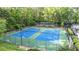 Two well-maintained tennis courts with blue and green surfacing, surrounded by fencing, landscaping, and mature trees at 3025 Mountain Creek Ne Ct, Roswell, GA 30075