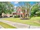 Charming two-story brick home with lush green lawn, mature tree and a two car garage at 3990 Madison Main Nw, Kennesaw, GA 30144