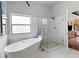 Bright bathroom with a soaking tub, glass shower, and neutral tile at 648 York View Dr, Auburn, GA 30011
