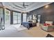 Primary bedroom featuring a dark accent wall, tray ceiling, several windows, and carpeted floor at 370 Beracah Sw Trl, Atlanta, GA 30331