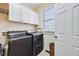 Laundry room with white cabinets, dark washer and dryer, and a window providing natural light at 370 Beracah Sw Trl, Atlanta, GA 30331