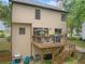 Back of house shows a wooden deck, bbq grill, and staircase down to yard at 404 Pine Grove Way, Woodstock, GA 30189