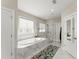 Modern bathroom featuring a soaking tub, large window, and tiled walk-in shower with glass doors at 2075 Parkhaven Ct, Roswell, GA 30076