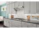 Kitchen with gray cabinets, tile backsplash, and stainless steel range hood at 2075 Parkhaven Ct, Roswell, GA 30076