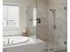 Tiled walk-in shower featuring a glass door, rainfall shower head, and a tiled bath at 2075 Parkhaven Ct, Roswell, GA 30076