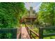 Picturesque backyard with wooden bridge, deck, mature trees, and lush landscaping, creating a serene retreat at 1885 N Creek Cir, Alpharetta, GA 30009