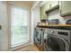 Modern laundry room with a front-loading washer and dryer, overhead cabinets, and a bright window at 1885 N Creek Cir, Alpharetta, GA 30009
