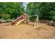 Community playground with slide, swings, and picnic tables surrounded by woodchips and trees at 1885 N Creek Cir, Alpharetta, GA 30009