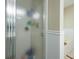 Bathroom shower with textured glass door and white trim, complemented by wood-paneling in the background at 1885 N Creek Cir, Alpharetta, GA 30009