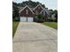 Two-story brick home with attached two-car garage featuring a long concrete driveway and mature landscaping at 3381 Walkers Ridge Rd, Dacula, GA 30019