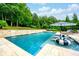 An inviting backyard pool with a sunbathing area, lush greenery, and comfortable lounge chairs for relaxation and leisure at 5963 Wild River Vw, Sugar Hill, GA 30518