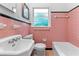 Retro pink tiled bathroom with a sink, toilet, and tub, all lit by a window at 1192 Willivee Dr, Decatur, GA 30033