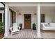 Welcoming front porch featuring a swing, a rocking chair and a rustic front door at 7114 Surrey Pt, Alpharetta, GA 30009