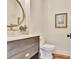 Elegant powder room with modern vanity, stylish round mirror, and hardwood floors at 210 4Th St, Fayetteville, GA 30214