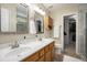 Bright bathroom featuring a double sink vanity, decorative mirrors, and a glass-enclosed shower at 325 Meadows Ln, Canton, GA 30114