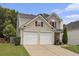 Two-story home with a two car garage, neutral siding, and landscaped front yard at 325 Meadows Ln, Canton, GA 30114