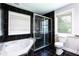 Bathroom with black tiled walls, large tub, walk-in shower with glass door, toilet, and large window at 1916 Highway 138 Sw, Conyers, GA 30094