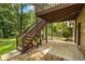 Backyard under deck features wooden stairs leading to an upper deck, with a stone patio area below at 3570 Bardfield Ct, Cumming, GA 30041