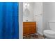 Cozy bathroom with wood vanity, decorative mirror, and a toilet; blue shower curtain in view at 3570 Bardfield Ct, Cumming, GA 30041