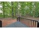 View from the back deck looking out onto a lush wooded backyard with a classic black railing at 7156 Whitfield Drive Dr, Riverdale, GA 30296