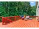 Orange painted wooden deck with outdoor furniture and lush greenery beyond at 1115 Ballington Dr, Cumming, GA 30041