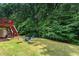 Lush backyard with mature trees, covered patio, and raised deck accessible from home at 1115 Ballington Dr, Cumming, GA 30041